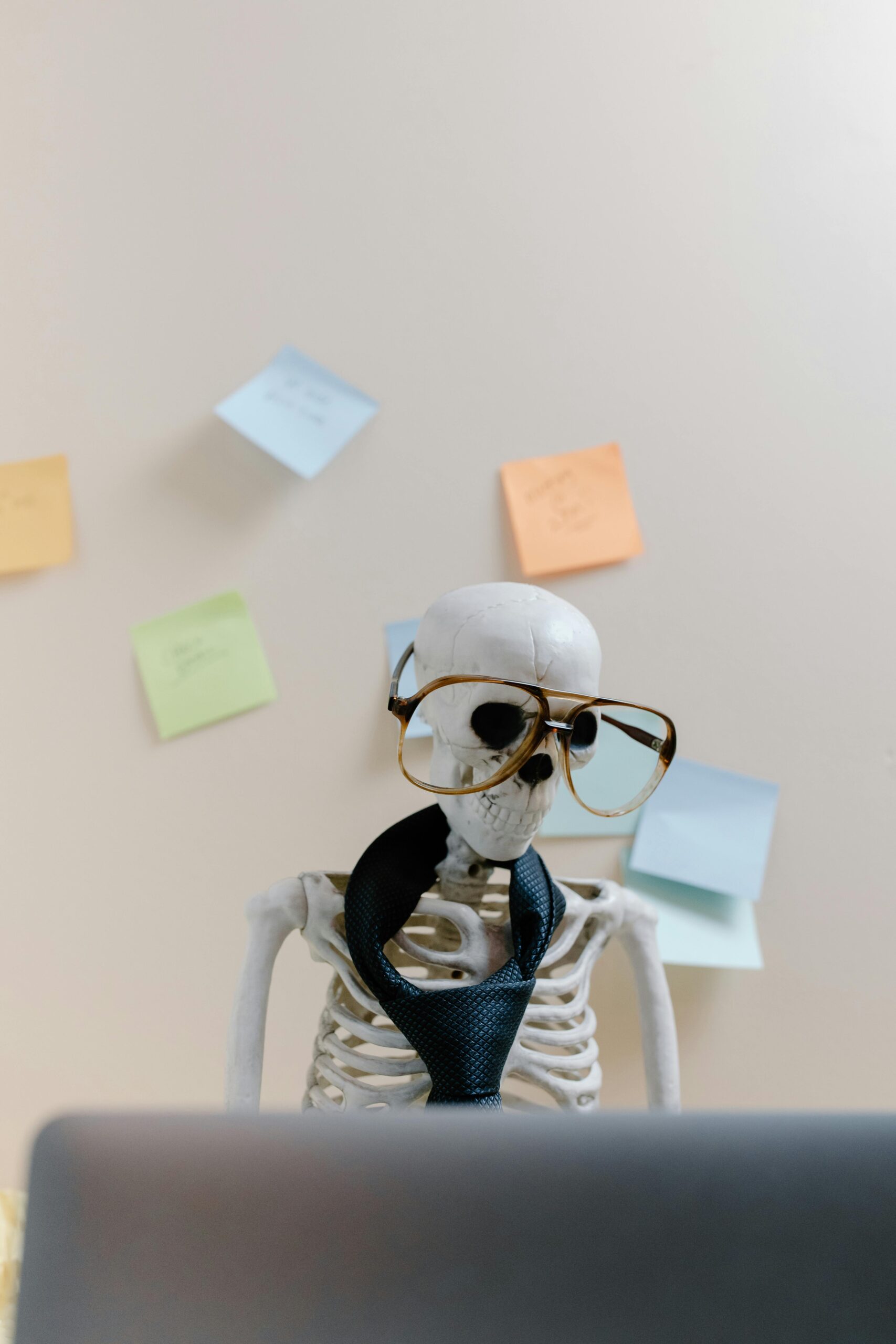 pexels-photo-8386712-8386712 Humorous skeleton model with glasses and tie, illustrating burnout and overwork in office environment.